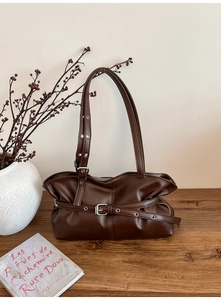 Détail du sac bandoulière en cuir marron foncé avec boucle argentée et sangle réglable