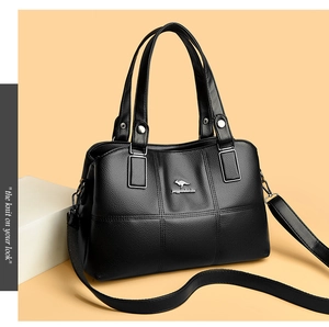 Détail du cuir grainé noir avec logo kangourou en métal argenté et surpiqûres précises