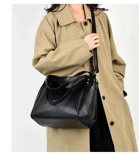 Detailed close-up of black lychee grain leather bucket bag with gold hardware and strap