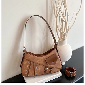 Detailed view of brown retro shoulder bag with metallic eyelets and strap on book decor