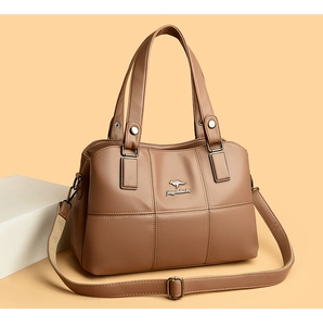 Détail du sac seau en cuir grainé montrant le logo et la bandoulière en toile