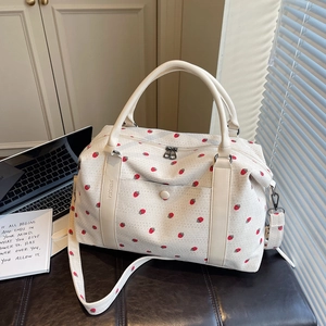 Corduroy travel bag with red strawberry pattern and dual handles in home setting