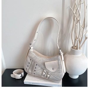 Close-up of saddle shoulder bag with metallic eyelets and small side pocket detail