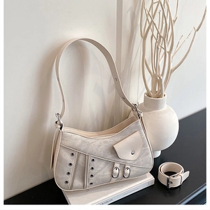 Detail view of cream leather shoulder bag with saddle design elements and metal buckles