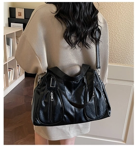 Detail of black pebbled leather tote bag with functional silver zippers and soft texture
