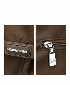 Detailopname van metalen logo-hardware en stoftextuur op een bruine draagtas