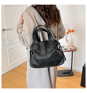 Detail of black lychee texture leather handbag with silver hardware and dual handles