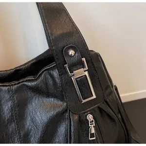 Close-up of shiny silver metal buckle and zipper on black lychee grain shoulder bag