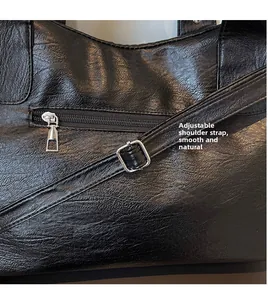 Detail of black tote bag showing lychee texture, zip pocket and adjustable strap