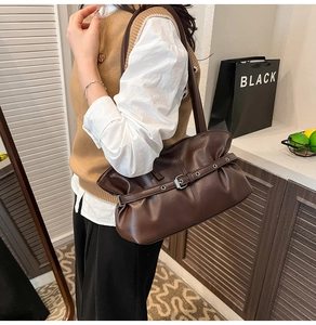 Détails d'un sac vintage marron foncé avec texture plissée et boucles métalliques