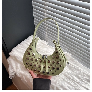 Detail of light green crescent bag featuring silver metal rivets and dual zipper closure
