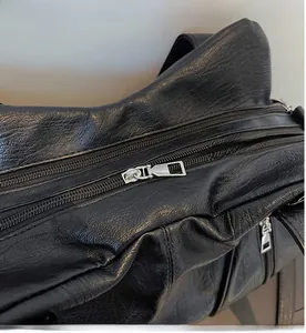 Close-up of smooth silver metal zipper on premium black textured leather tote bag
