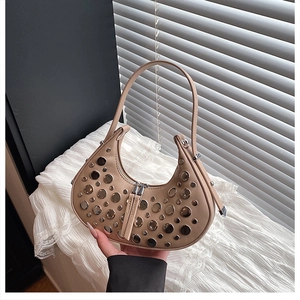 Close-up of beige crescent bag with silver stud details and metal rivets on leather