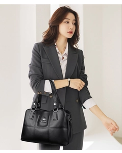 Détail du sac seau en cuir noir grainé avec logo argenté et surpiqûres matelassées