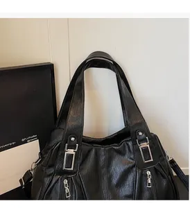 Detail of black leather tote bag featuring silver square buckle and double outer zip pockets
