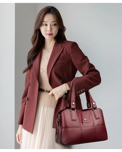 Détail d'un sac seau en cuir bordeaux avec logo kangourou et boucles métalliques dorées