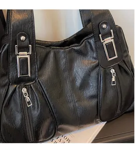 Close-up of black leather tote bag featuring oily texture and silver metal buckle detail