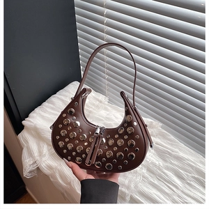 Detail of a brown crescent shoulder bag with silver rivet studs and a long zipper puller