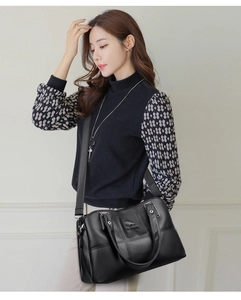 Détail d'un sac noir en cuir grainé avec logo kangourou et finitions métalliques argentées