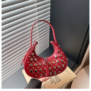 Detail of red hobo bag with silver metallic studs on leather, placed on books