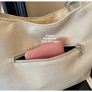 Detail view of the rear zipper pocket on a beige vintage faux leather tote bag for storage