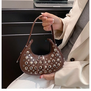 Detail of brown leather moon bag featuring silver rivets and secure double zip closure