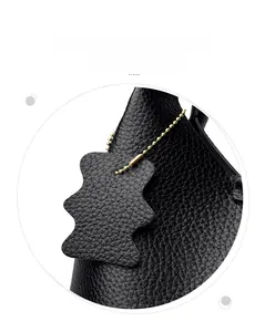 Détail d'un sac à main en cuir grainé noir avec charme assorti et chaîne à billes dorée