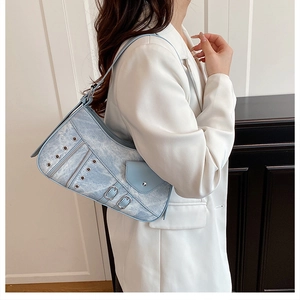 Detail of light blue denim shoulder bag with silver eyelets and buckle accents