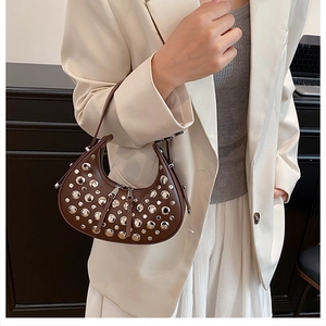 Detail of dark brown crescent bag with silver rivet studs on a female model
