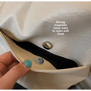 Detail of the strong magnetic buckle closure on a beige leather tote bag with black lining