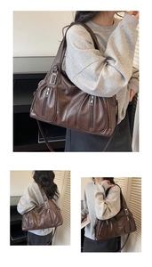 Detail view of dark brown tote bag featuring decorative silver zippers and leather texture