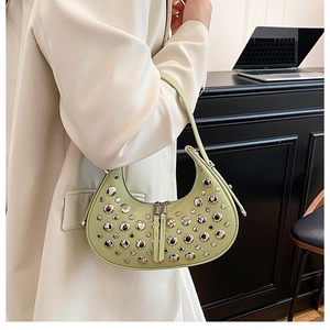 Detail of light green crescent underarm bag with silver studs on a stylish model