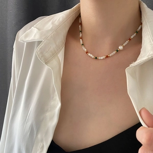 Freshwater pearl and colorful beaded necklace with gold accents worn on a white shirt