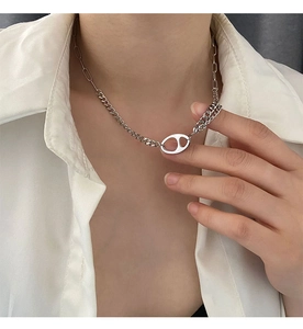 Vue détaillée du pendentif nez de porc argenté sur une chaîne asymétrique polie