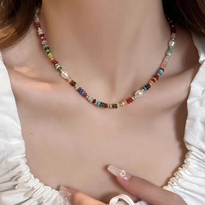 Kleurrijke kralenketting met zoetwaterparels en gouden kralen op een model sleutelbeen