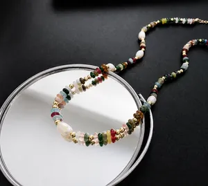 Detailopname van een kleurrijke boho-kralenketting met zoetwaterparels op spiegel