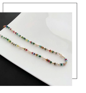Detailopname van een boho-parelketting met zoetwaterparels en kleurrijke stenen op een bord