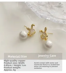 Détail de boucles d'oreilles lapin dorées avec zircon et perle blanche ronde