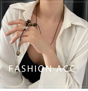 Detail of hand-woven cord necklace featuring tiger eye beads and silver butterfly pendant