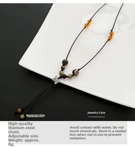 Detail of butterfly titanium steel pendant with braided cord and amber beads