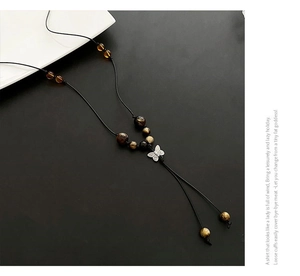 Detail of butterfly pendant with tiger eye beads on a black woven cord necklace