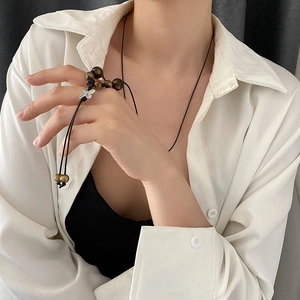 Tiger eye bead necklace with silver butterfly pendant on model in white shirt
