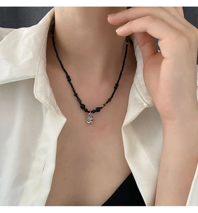 Nahaufnahme einer Perlenkette mit silbernem Löwenkopf-Anhänger am Hals des Models