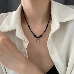 Moderne Perlenkette mit Löwenanhänger und Bernsteinperlen auf weißem Hemd