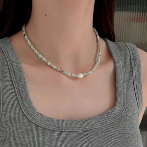 Elegant beaded necklace with light blue stones and central white pearl worn by a model