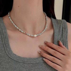 Detail of light green beaded necklace featuring a central white pearl and gold spacers
