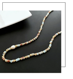 Detail of colorful natural stone beads and large white pearl on luxury beaded necklace
