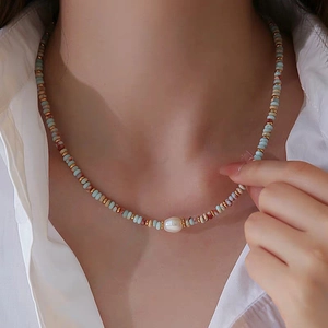 Boho beaded necklace with natural stones and pearl pendant on a white shirt