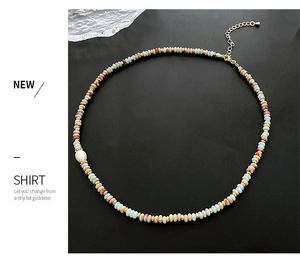 Detail of beaded necklace with natural stones and a baroque pearl on a black texture