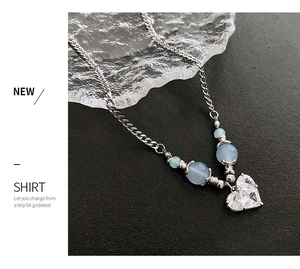 Détail du collier chaîne argenté avec perles bleues et pendentif double cœur en zircon